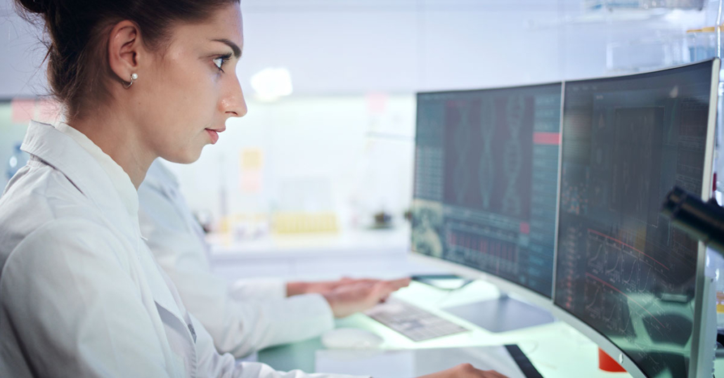 Oncology Data Specialist looking closely at data on a computer screen.