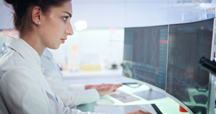 Oncology Data Specialist looking closely at data on a computer screen.