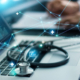 Laptop with stethoscope and Physician's hands in the background. Medical data icons and connection points overlay the image.